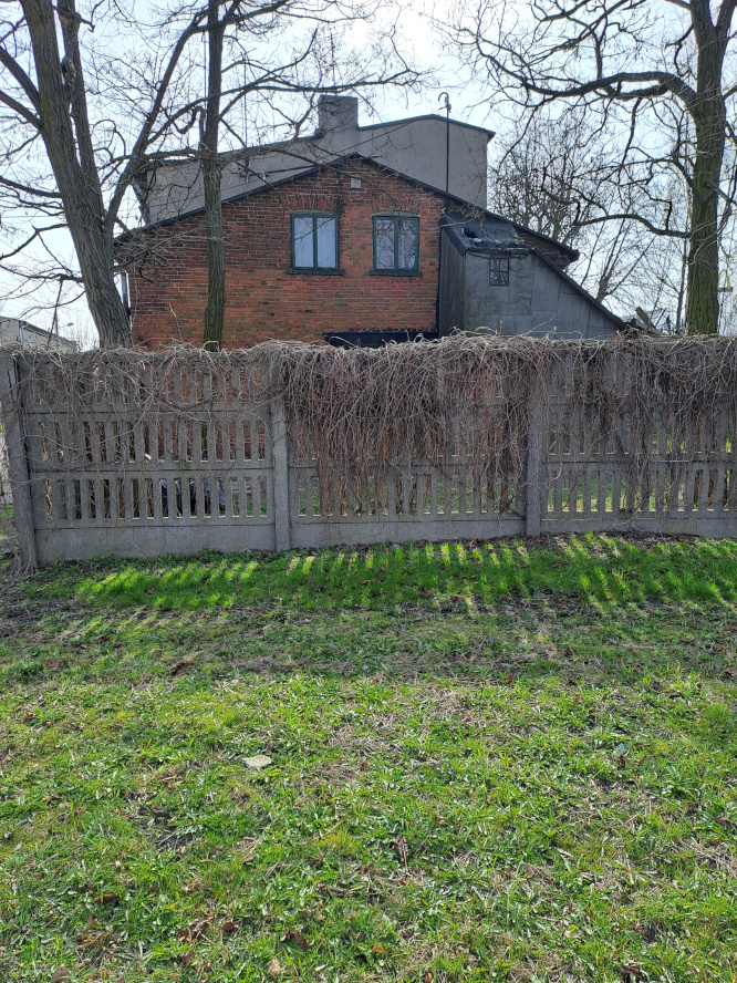 betonowe ogrodzenie z domem w tle