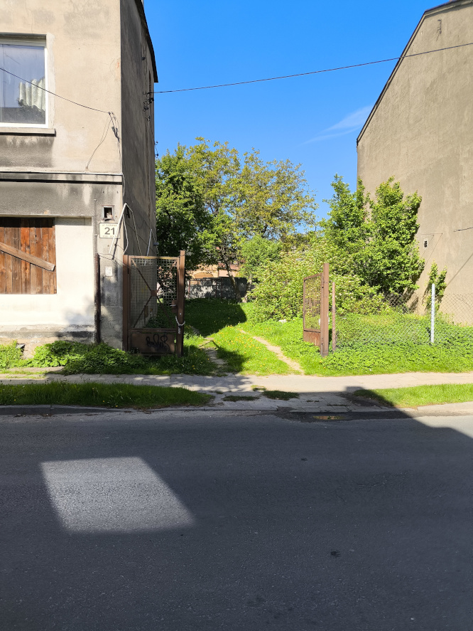 stalowa brama wjazdowa na podwórko porośnięte trawą