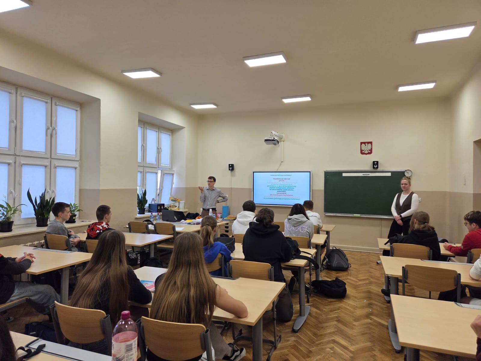 uczniowie siedzący w klasie podczas prezentacji