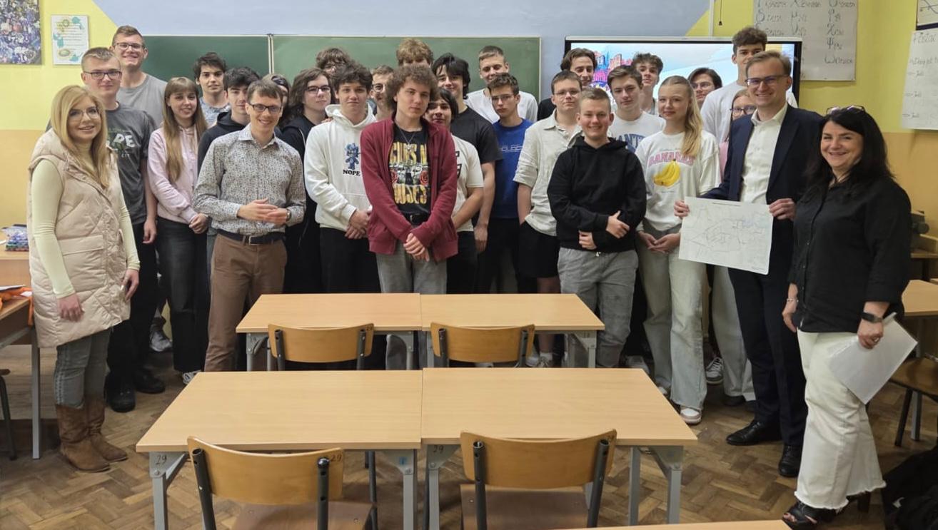 grupa uczniów stojących pod tablicą 